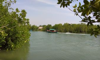 a boat is sailing on a river , passing through lush green vegetation with trees and buildings in the background at Stella Resort