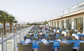 a large outdoor dining area with many tables and chairs , all set for a meal at Palm Wings Kusadasi Beach Resort&Spa