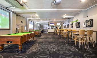 a large room with multiple pool tables , couches , and chairs , as well as people sitting at tables at Nightcap at the Charles Hotel