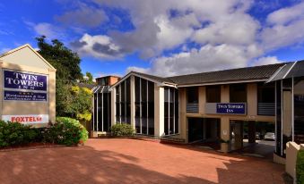 "a modern building with a large glass entrance and the sign "" twin towers "" on it" at Twin Towers Inn