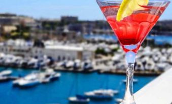 a cocktail with a lemon slice garnish is served in a glass , overlooking a marina filled with boats at Hotel Kennedy Nova