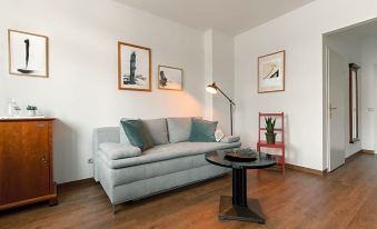 a modern living room with a white couch , wooden floors , and three framed pictures on the wall at Hotel Esplanade