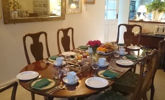 a dining table is set with plates , silverware , and a vase of flowers in the center at Stone House