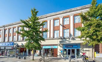 a building with a blue sign and white trim , featuring several bicycles parked outside on the sidewalk at Travelodge Leatherhead