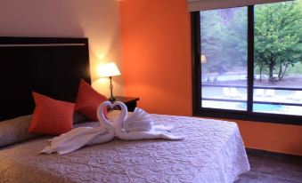 a cozy bedroom with a large bed , two white towels arranged in the shape of swans on the bed at Cabañas Del Sol