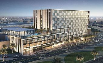 a modern , multi - level building with a large glass facade and a parking lot in front of it at Waldorf Astoria Kuwait