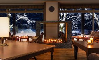 a dining room with a large fire pit in the middle of the room , surrounded by several chairs and tables at Courtyard by Marriott Hakuba