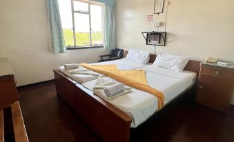 a bedroom with a large bed , wooden furniture , and a window with curtains , giving it a cozy and inviting atmosphere at Plaza Hotel