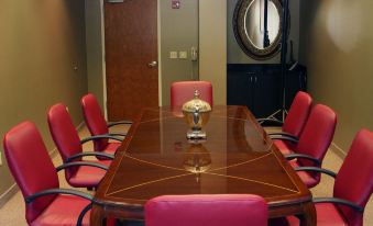 a conference room with a large wooden table surrounded by pink chairs and a chandelier at Holiday Inn Carbondale-Conference Center