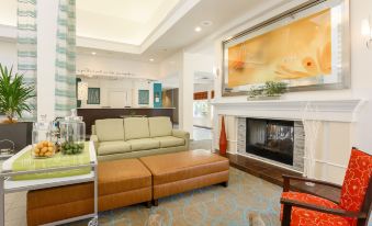 a cozy living room with a fireplace , comfortable couches , and a tv mounted on the wall at Hilton Garden Inn Nanuet