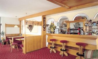 a cozy hotel lobby with wooden furniture , red carpet , and various decorations , including a bar area at Hotel Olympia