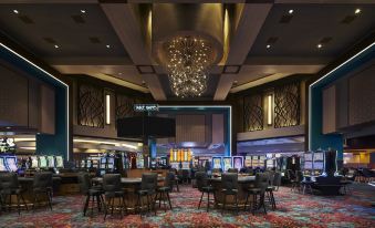 a large , well - lit casino lobby with multiple gaming tables and couches , as well as a chandelier hanging above at Harrah's Ak-Chin Casino Resort