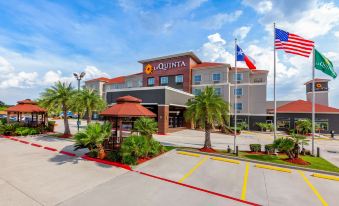 "a large , red - roofed building with the name "" la quinta inn & suites "" prominently displayed on it , surrounded by palm trees" at La Quinta Inn & Suites by Wyndham Houston Channelview