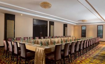 a long dining table is set with wine glasses , bottles , and candles in a hotel room at Best Western Plus Makassar Beach