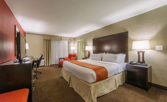 a large bed with orange and white linens is in a room with two lamps , a desk , and chairs at Hotel Mtk Mount Kisco