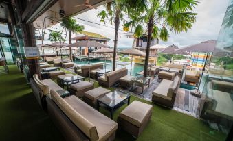 an outdoor seating area at a resort , with several couches and chairs arranged around a pool at ABC Hotel