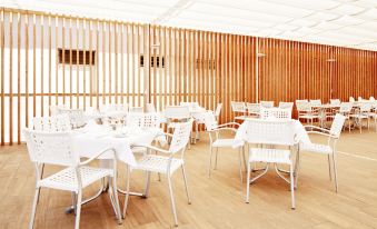 an empty dining room with white tables and chairs , wooden walls , and a skylight above at Globales Los Delfines