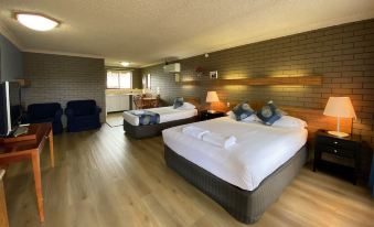 a hotel room with two beds , one on the left and one on the right side of the room at Tumut Valley Motel