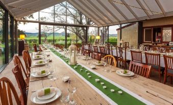 a long wooden dining table set for a formal event , with multiple chairs arranged around it at Ratho Farm