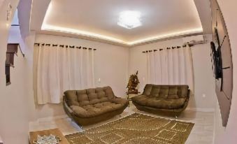a spacious living room with two brown sofas , a coffee table , and large windows covered in white curtains at North Hotel - Aeroporto