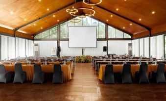 a large conference room with multiple rows of chairs arranged in a semicircle around a projector screen at Horison Green Forest Bandung
