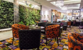 a modern restaurant with various seating options , including chairs and couches , under a large chandelier at Hotel Verde Cape Town Airport