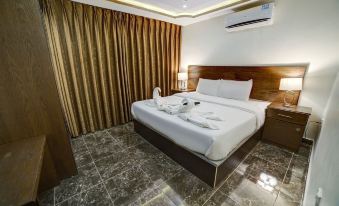 a large bed with white linens and a wooden headboard is situated in a room with brown curtains at Taj Hotel