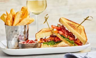 a plate of food with a sandwich , fries , and a glass of wine on a table at Courtyard Baltimore Hunt Valley