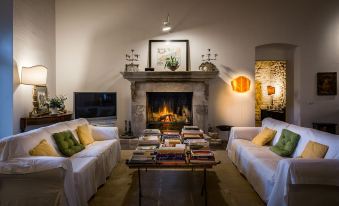 a cozy living room with a fireplace , two couches , and a television mounted on the wall at Baglio Occhipinti