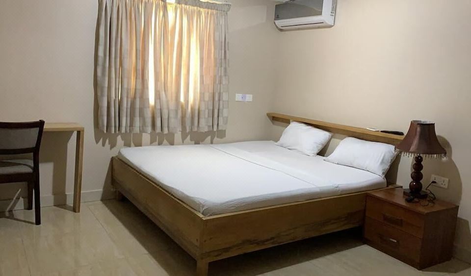 a neatly made bed with white sheets and pillows , situated in a room with wooden flooring and a window with curtains at The Float