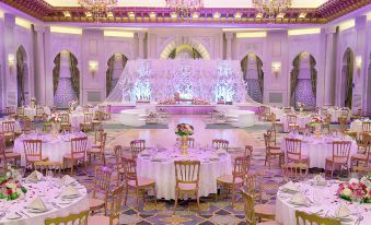 a beautifully decorated banquet hall with tables , chairs , and chandeliers , set for a formal event at Hilton Suites Makkah