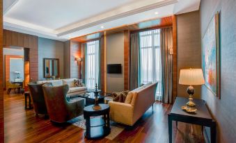 a spacious living room with hardwood floors , a large flat - screen tv mounted on the wall , and multiple couches and chairs arranged in the at Sheraton Grand Samsun Hotel