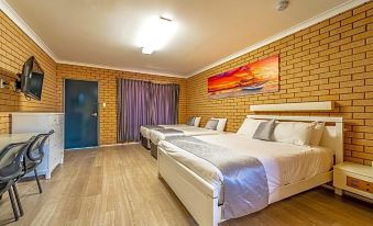 a hotel room with three beds , one on the left , one in the middle , and one on the right at Carnarvon Motel