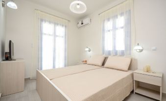 a white bedroom with two beds , one on the left and one on the right side of the room at Natura Villas in Naxos