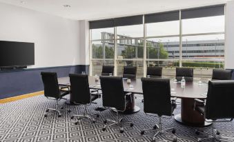 a conference room with a large table surrounded by chairs , and a television mounted on the wall at Sofitel London Gatwick