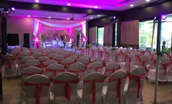 a wedding venue with rows of white chairs arranged for an event , surrounded by pink and purple lights at Riva Beach Resort
