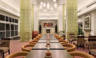 a long dining table set up in a hotel lobby , with chairs arranged around it at Hilton Garden Inn Akron-Canton Airport