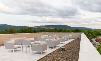 a rooftop patio with several lounge chairs arranged in rows , overlooking a beautiful view of the mountains at Quirk Hotel Charlottesville