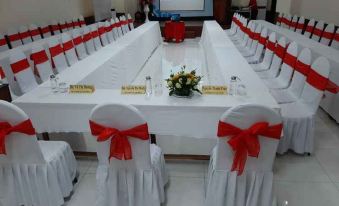 a long white table with red bows and chairs set up for a formal event at Sao Mai Hotel