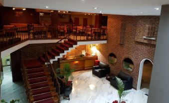 a spacious room with a brick wall and a staircase leading up to the second floor at Hotel Presidente