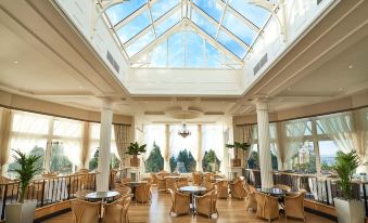 a large , well - lit restaurant with multiple dining tables and chairs , as well as a skylight above the tables at Crieff Hydro