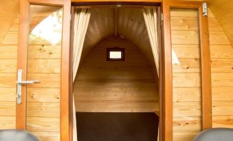 a wooden cabin with two doors , one on the left and one on the right , leading to an open doorway at YHA Malham