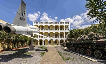 a large white building with a military theme , featuring a large tank on the ground and a model airplane in front of it at Country Home