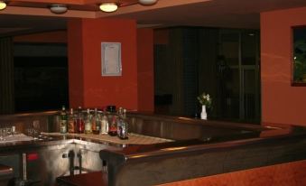 a well - lit bar area with multiple bottles of liquor on display , and a dining table nearby at Zlatibor Hotel