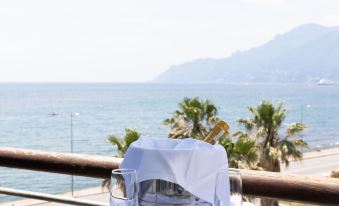 a table with a glass and silverware is set on a balcony overlooking the ocean at Grand Hotel Salerno