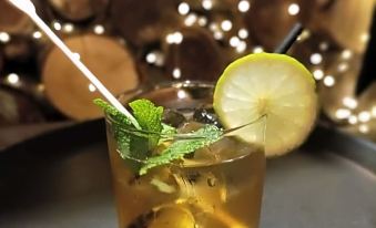 a glass filled with a drink garnished with mint leaves and a lemon wedge on a wooden table at Seven Stars