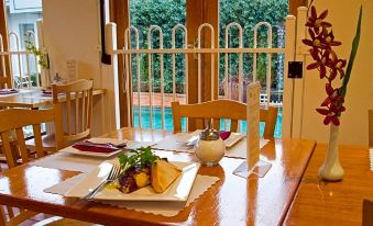 a dining table set with plates , bowls , and cups , along with a view of the pool through a white railing at Admiralty Inn