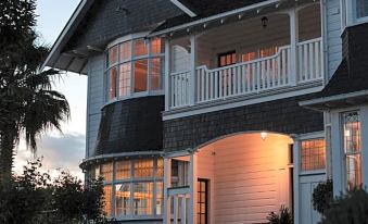 a large house with a white picket fence and black trim is illuminated at night at Cedar House