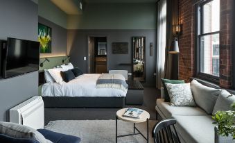 a modern bedroom with a large bed , white bedding , and a couch in the living room at The Chamberson