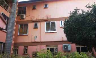 a pink apartment building with air conditioning units on the side and a window next to it at DaysInn Hotel